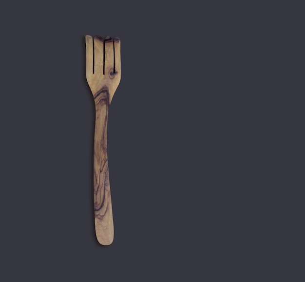 Top up view olive wooden cook serve fork isolated on dark background suitable for your design element