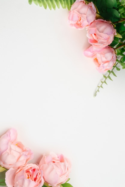 Photo top vertical view of pink peonies artificial flowers  and green fern leaves on white blank background