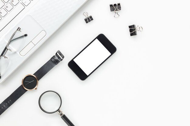 Photo top view accessories business office desk.mobile phone,laptop,watch,clipboard,eyeglasses,magnifier on white office desk with copy space.