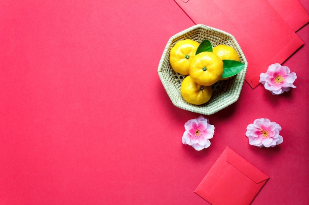 Top view accessories Chinese new year festival decorations.orange,leaf,wood basket,red packet,plum blossom on red background.