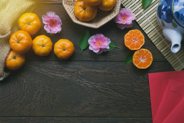 Top view accessories Chinese new year festival decorations.orange,leaf,wood basket,red packet,plum blossom,teapot on wooden table background.