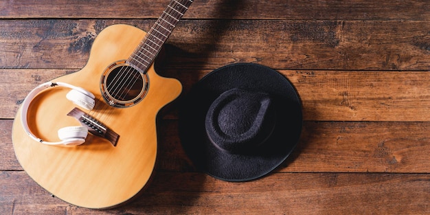 Top view acoustic guitars with earphones and hipster hats on\
old wooden backgroundflat lay