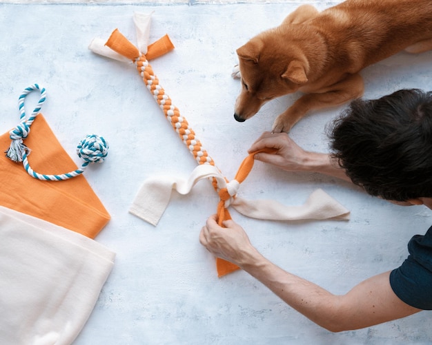 Photo top view of adult man making diy homemade educational toys for dogs using fleece fabric stripes