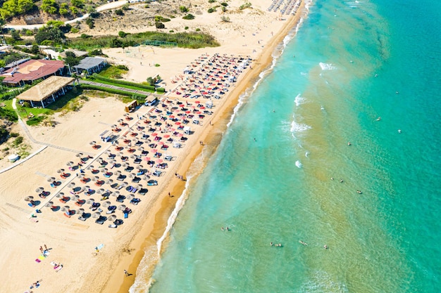 Top view aerial drone photo of Banana beach with beautiful turquoise water sea waves and red umbrellas Vacation travel background Ionian sea Zakynthos Island Greece