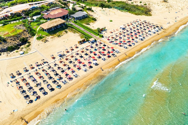 Top view aerial drone photo of Banana beach with beautiful turquoise water sea waves and red umbrellas Vacation travel background Ionian sea Zakynthos Island Greece