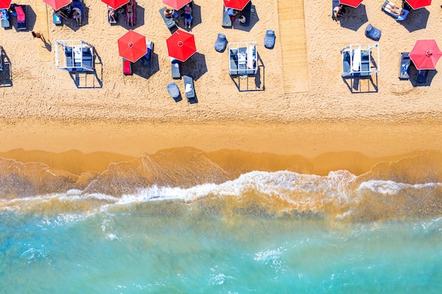 Top view aerial drone photo of Banana beach with beautiful turquoise water sea waves and red umbrellas Vacation travel background Ionian sea Zakynthos Island Greece