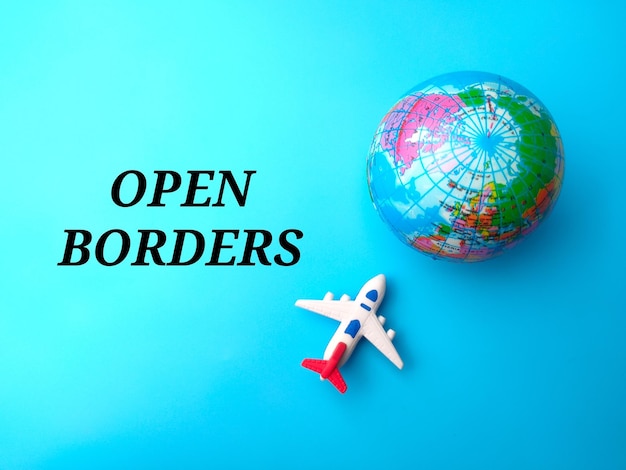 Top view airplane and earth globe with text OPEN BORDERS on blue background