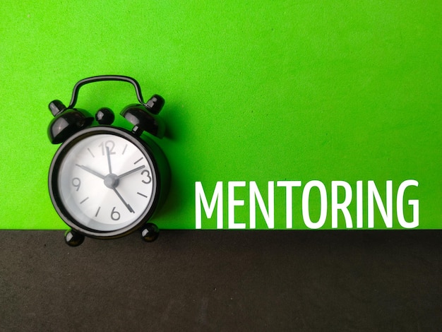 Будильник сверху с текстом MENTORING на зеленом и черном фоне