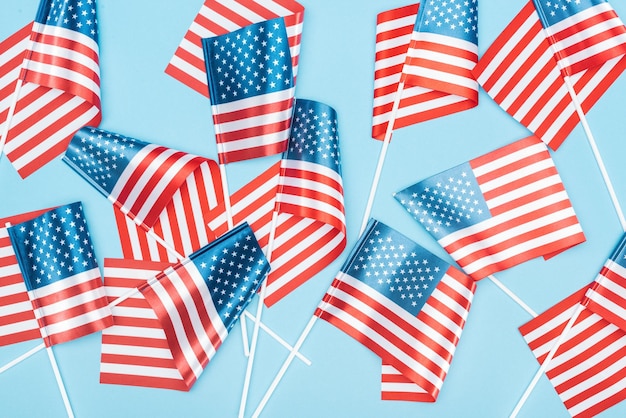 Top view of american flags on sticks scattered on blue background