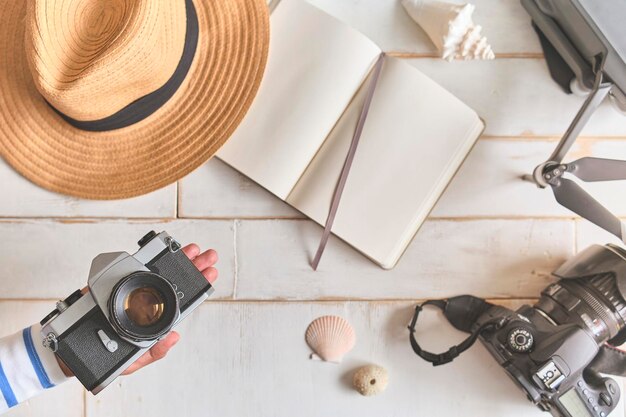 Photo top view of an analog camera and a notebook on a wooden