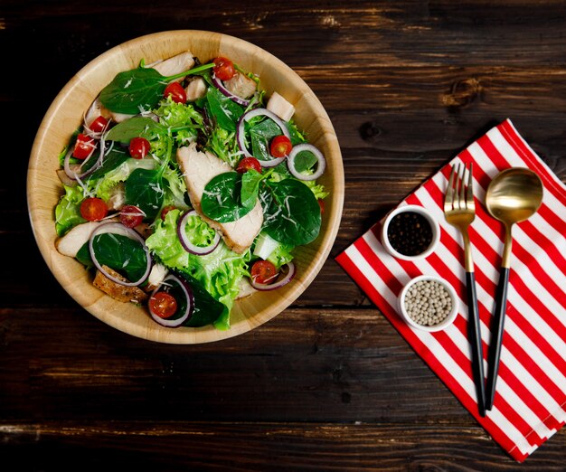 Top view angle photo of grilled chicken breast fresh and fillet vegetable salad with a variety of kinds of natural vegetables in wooden bowl on wood background. Healthy and diet menu idea.