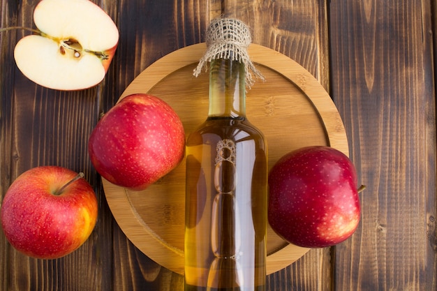 Top view of apple vinegar cider in the glass bottle on the round cutting board