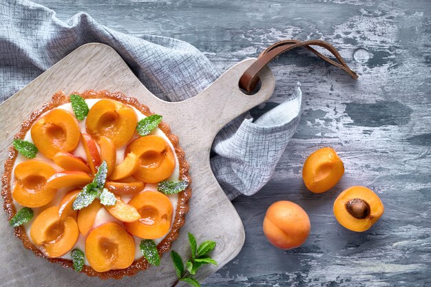 Top view of apricot tart with mint leaf on textured background