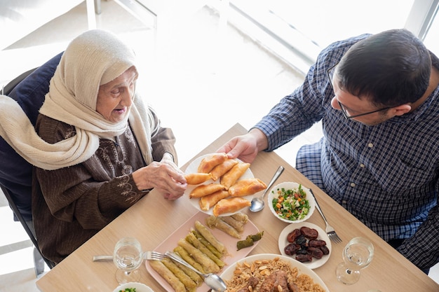 Foto top view arabische familie die samen eten op een houten tafel met vader, moeder, grootvader, grootmoeder en zoon