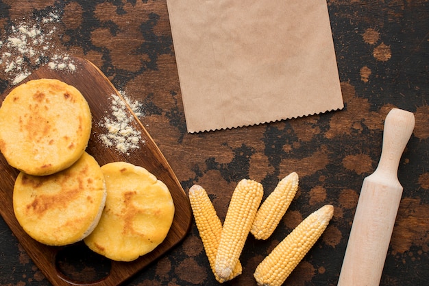 Top view arepas on wooden board and corn