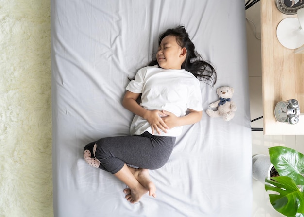 Top view Asian child little girl in her bed has a stomachache healthy idea concept