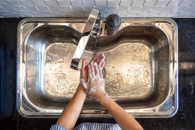 Top view Asian woman hand washing with faucet water in kitchen at home