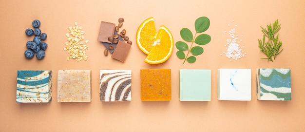 Photo top view of assorted variety of different handmade soap bars with natural ingredients, herbs, berries. skin care and organic soap making concept, spa cosmetic treatment