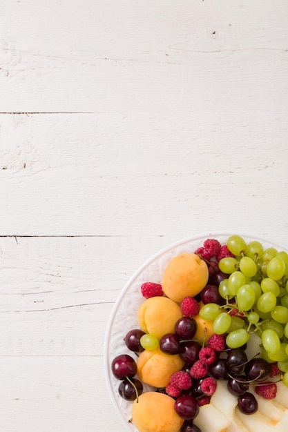 白いプレートと白いテーブルの背景にジューシーなフルーツの品揃えの上面図