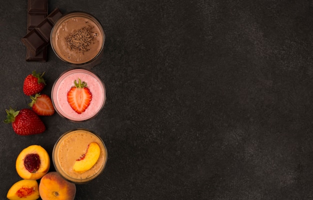 Top view of assortment of milkshakes with fruits and chocolate with copy space