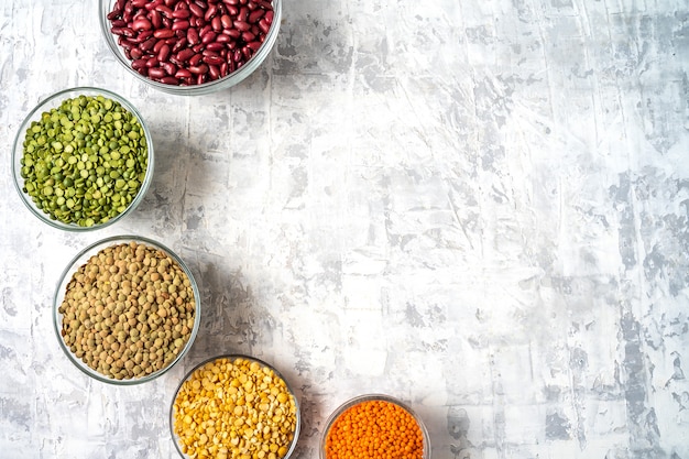 Top view of assortment of peas, lentils, beans and legumes over white background.