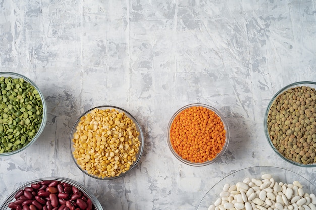 Top view of assortment of peas, lentils, beans and legumes over white background.