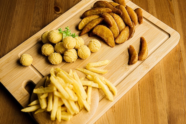 Vista dall'alto di assortimento di patate patate fritte al forno su un piatto di legno servito con salsa di pomodoro patatine fritte spicchi crocchette di patate purè di patate polpette impanate e fritte lato campagna