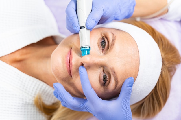 Top view of an attractive calm Caucasian middle-aged lady relaxing during a skin exfoliating procedure