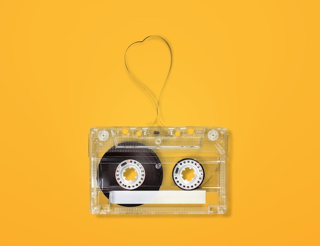 Photo top view of audio cassette with tangled tape on bright yellow background with copy space