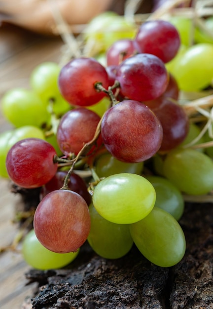 Top  view of autumn background with black and white grapes on tree bark and straw