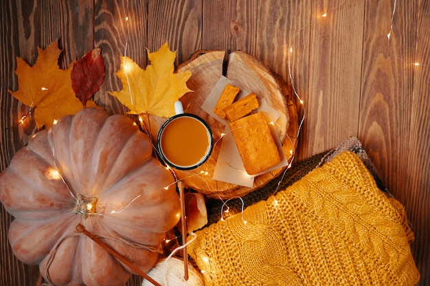 Top view of autumn composition with cup pumpkin pie and sweater pumpkin juice and sweet freshly bake...