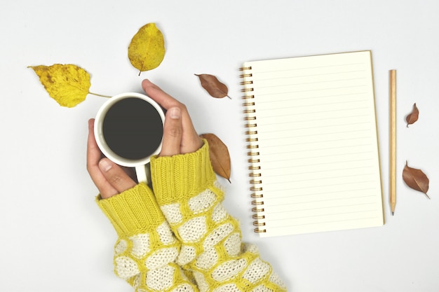 Top view of autumn leaves with coffee and notebook