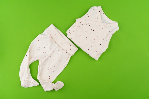 Top view of baby clothes on green background