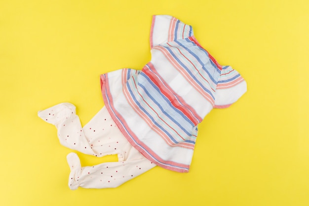 Top view of baby girl clothes on yellow background