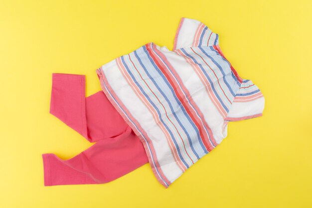 Top view of baby girl clothes on yellow background