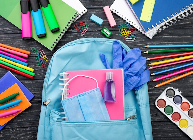 Photo top view of back to school stationery with backpack and gloves