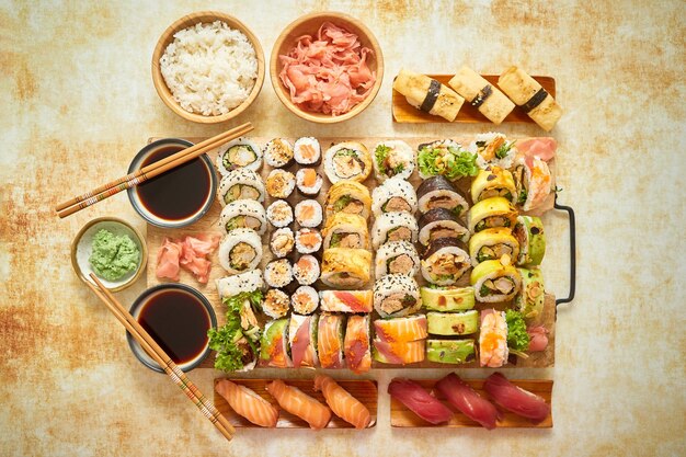 Top view background with set of colorful different kinds of sushi rolls placed on wooden board Flat lay