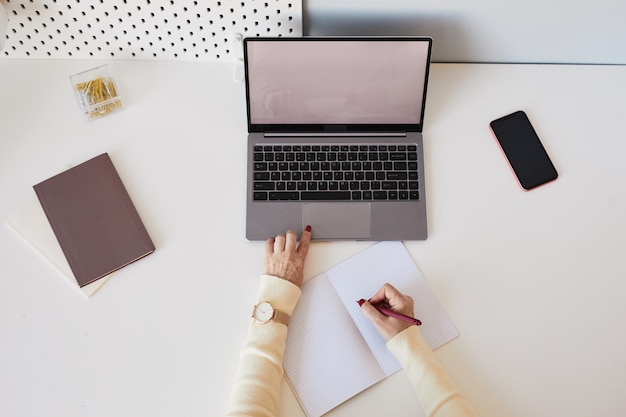 Vista dall'alto dello sfondo della donna che utilizza il computer portatile con lo schermo vuoto sullo spazio bianco della copia del posto di lavoro dell'ufficio domestico