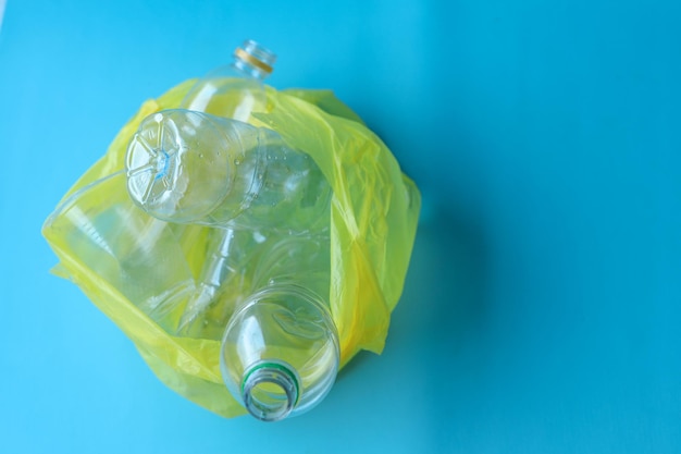 Вид сверху на мешок мусора из пластиковых бутылок на синем фоне.
