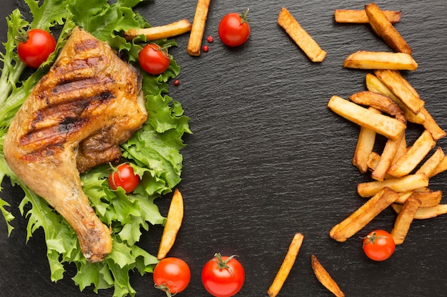 Foto vista dall'alto di pollo al forno e pomodorini con patatine fritte