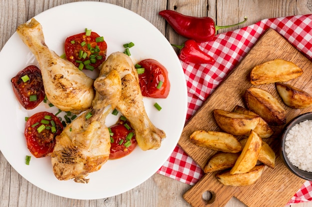 Top view baked chicken and tomatoes on plate with wedges