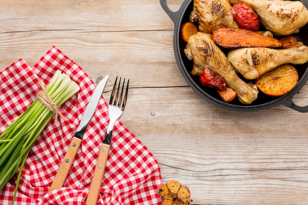 Top view baked chicken and veggies in pan with cutlery