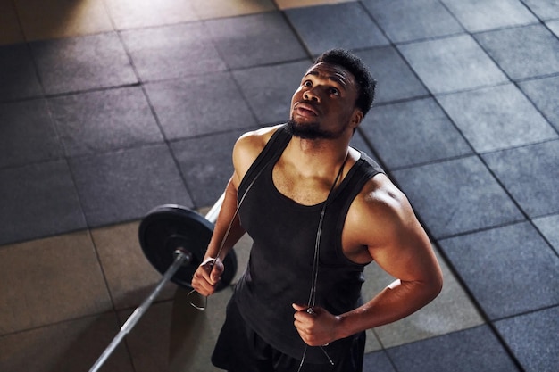 Top view Barbell on the floor Strong african american man in sportive clothes have workout day in the gym