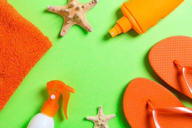 Top view of Beach flat lay accessories. sunscreen bottle with seashells, starfish, towel and flip-flop