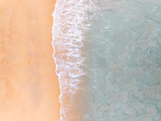 Top view beach with waves crashing on sandy shoreBeautiful waves sea surface in summer seascape backgroundAmazing beach colorful water background