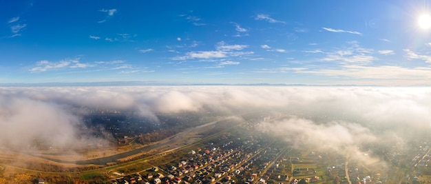 Vista dall'alto del bel cielo azzurro con nuvole e vista degli edifici residenziali vicino ai campi.