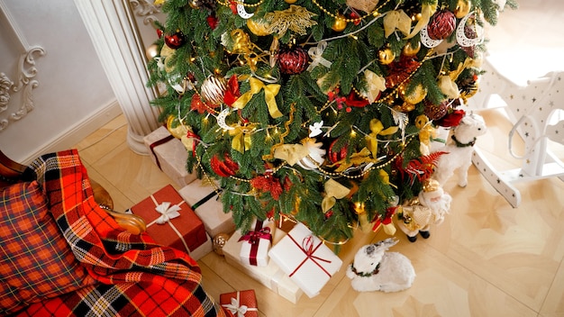 Top view of beautiful Christmas tree in living room decorated with light garlands and golden baubles. Winter holidays background or backdrop.