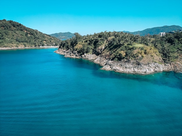 Top view of the beautiful coast of an isolated island around which clear blue water with inspiring waves