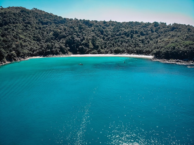 Top view of the beautiful coast of an isolated island around which clear blue water with inspiring waves