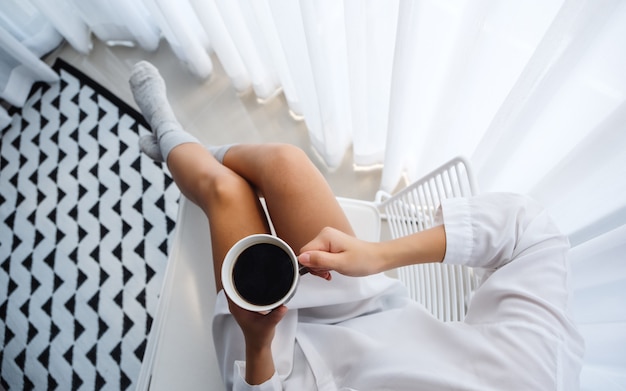 Top view  of a beautiful woman drinking hot coffee in bedroom at home in the morning